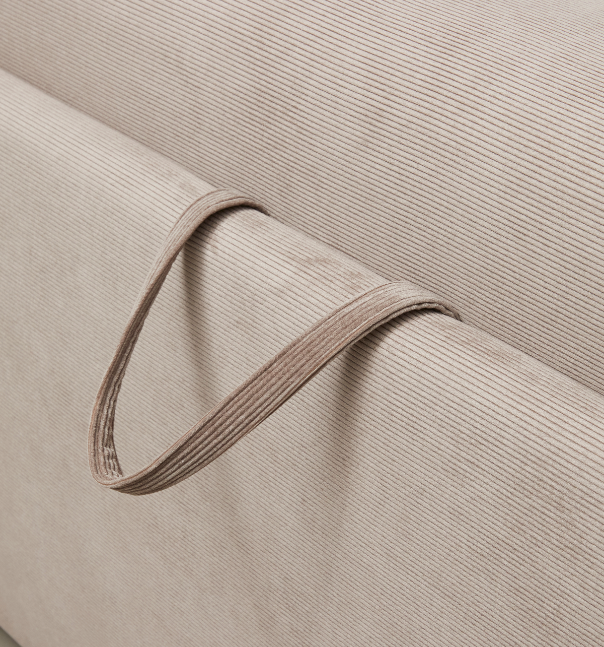 Närbild av beige ribbad textil med en smal tygögla i samma material.
