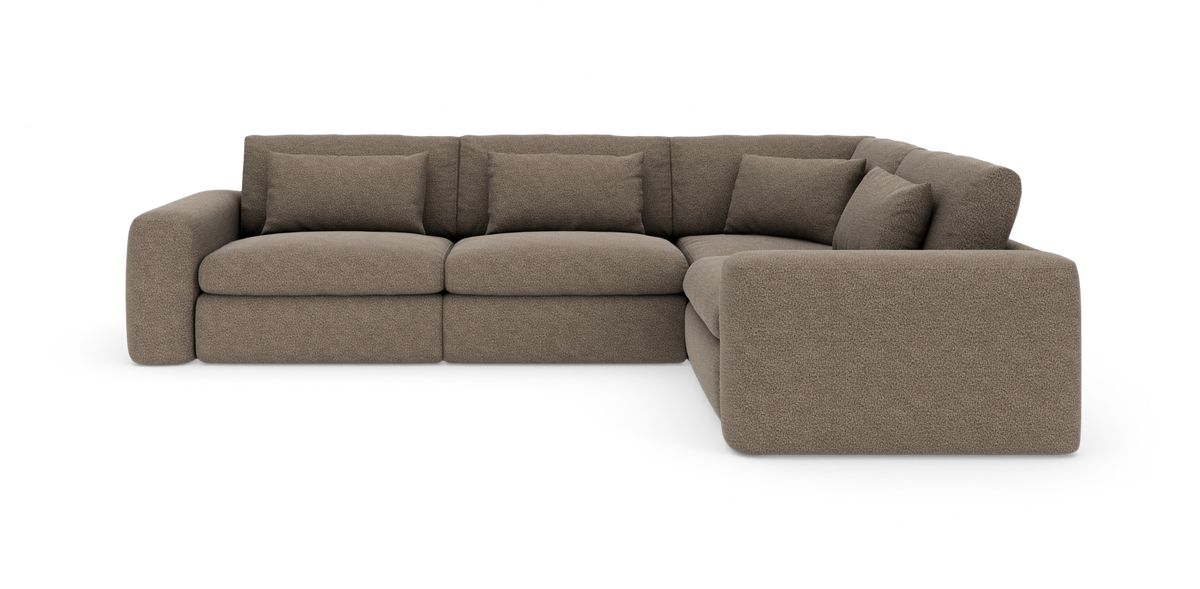 Brun modulsoffa i hörnmodell med rundade armstöd och fem ryggkuddar, frilagd på vit bakgrund.