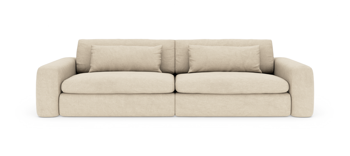 Beigefärgad modern soffa med mjuka runda armstöd och två avlånga kuddar, frilagd på vit bakgrund.