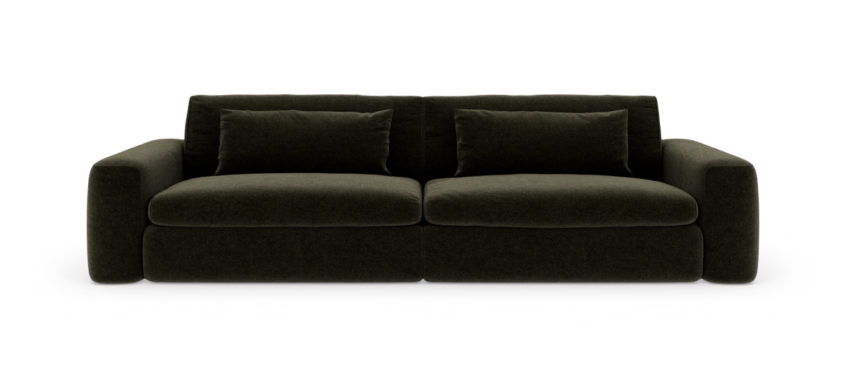 Mörkgrön, modern soffa med tjocka kuddar, frilagd mot vit bakgrund.