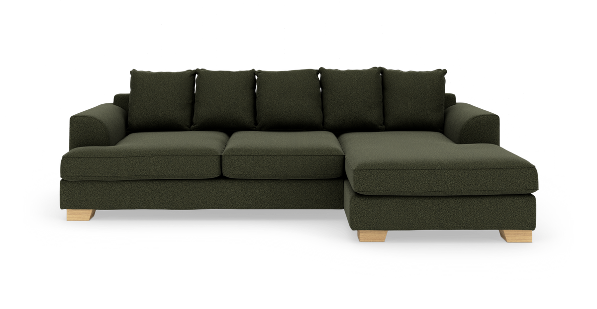 Mörkgrön 4‑sits soffa med schäslong till höger och ljusa träben, frilagd mot vit bakgrund.