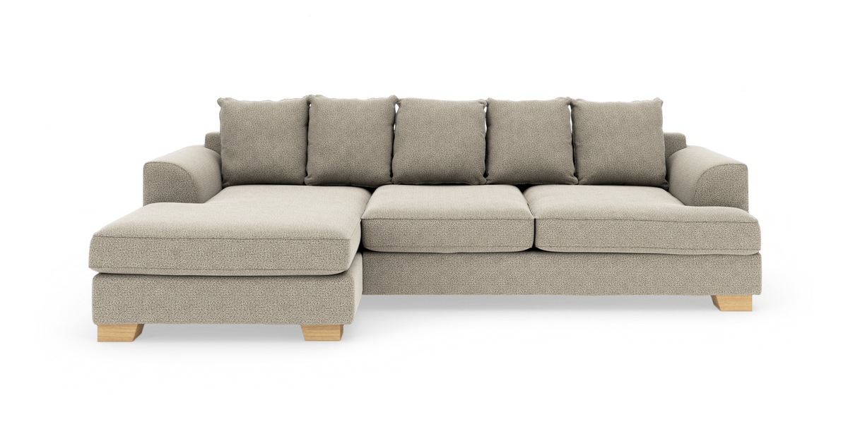 Beige hörnsoffa med vänster divan, fem ryggkuddar och ljusa träben, frilagd mot vit bakgrund.