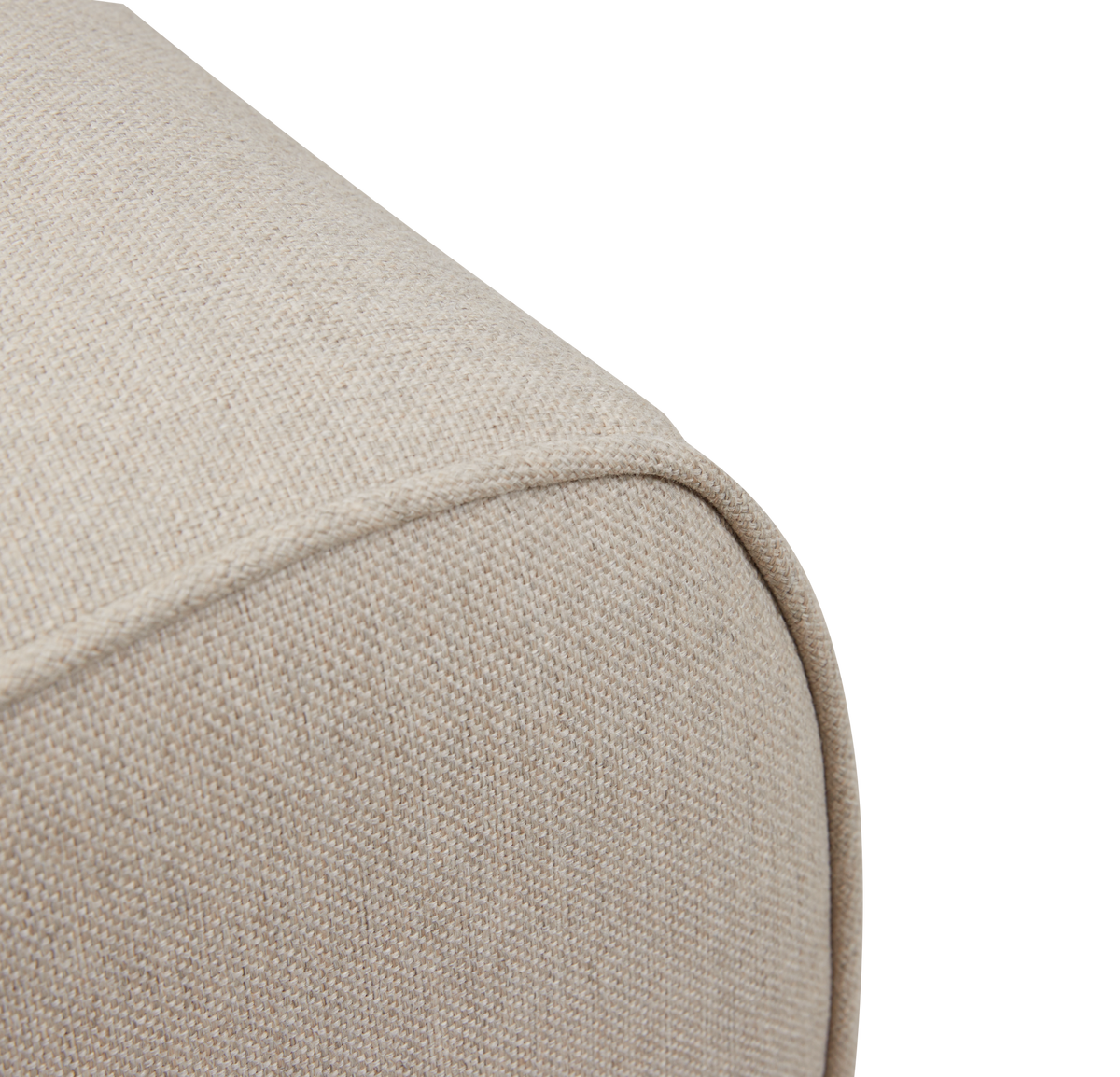 Närbild av beige textilklädsel med passpoal på rundad soffkant.