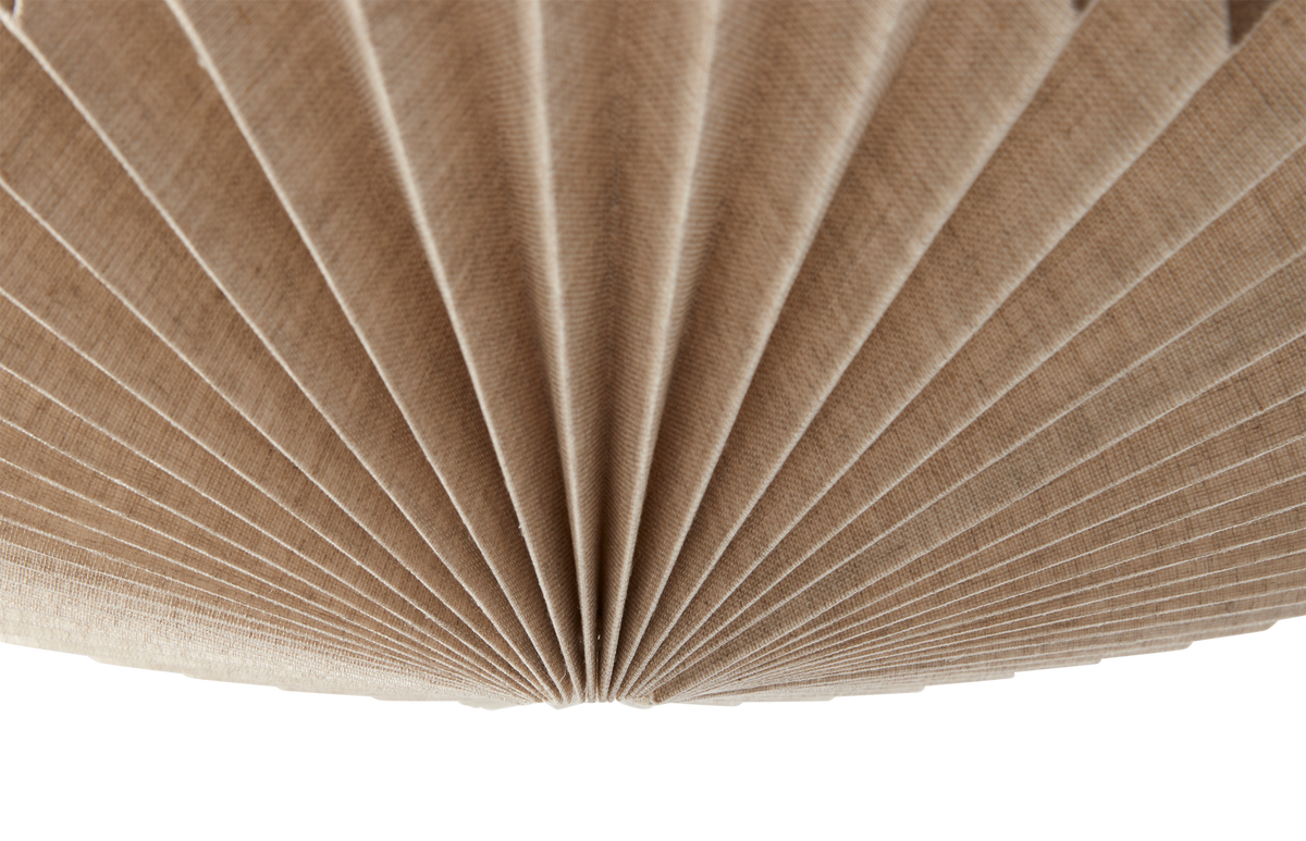 Närbild av en beige, plisserad tygskärm till lampa sedd underifrån.