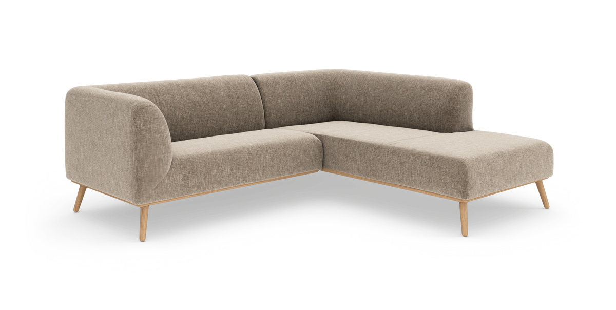 Beige L‑soffa i tyg med rundade hörn och ben i ljust trä, frilagd mot vit bakgrund.