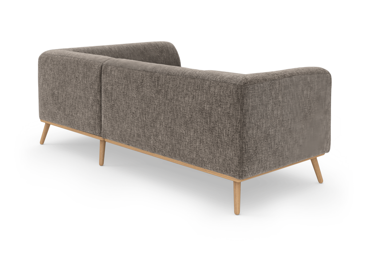 Grå tygsoffa i modern, skandinavisk stil med ljusa träben, sedd snett bakifrån på neutral bakgrund.