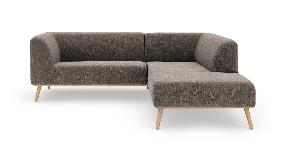 L‑formad modulsoffa i mörkgrå textil med ljusa träben, frilagd på vit bakgrund.