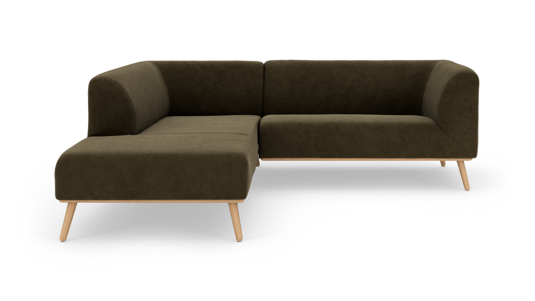 Mörk olivgrön L‑soffa med träben, fristående mot vit bakgrund.