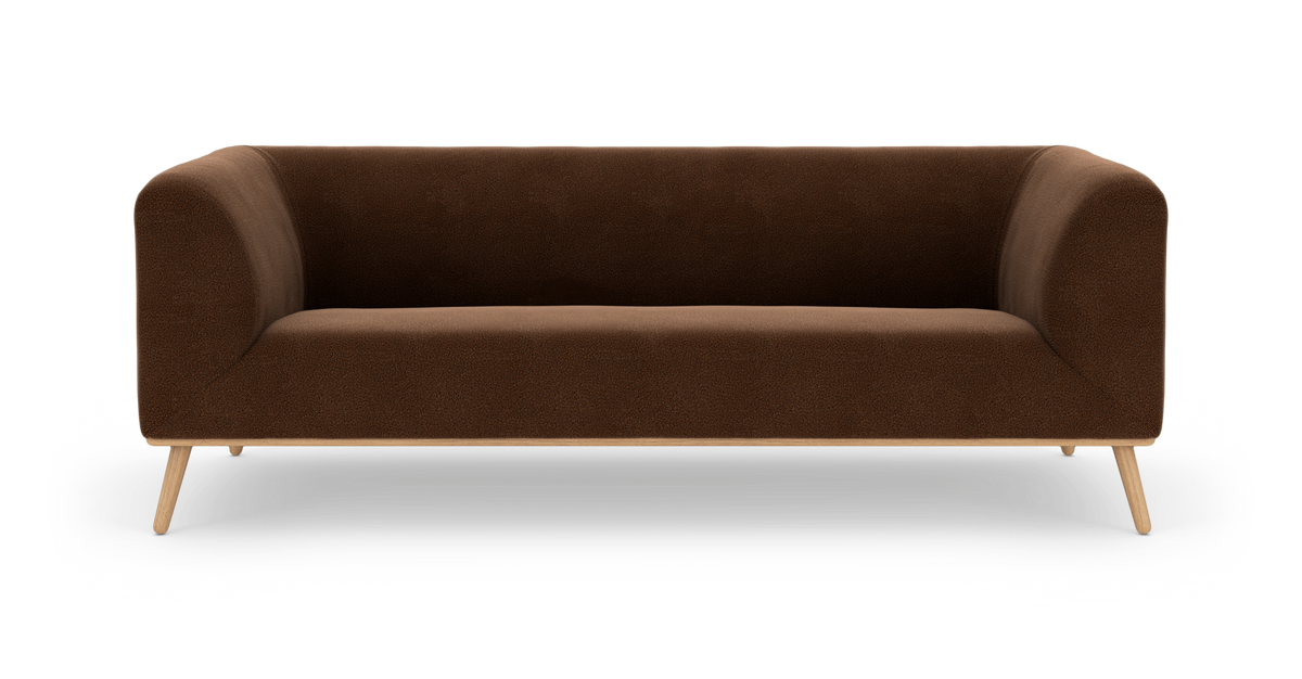 Brun modern 3-sits soffa med rundade armstöd och träben, frilagd mot vit bakgrund.