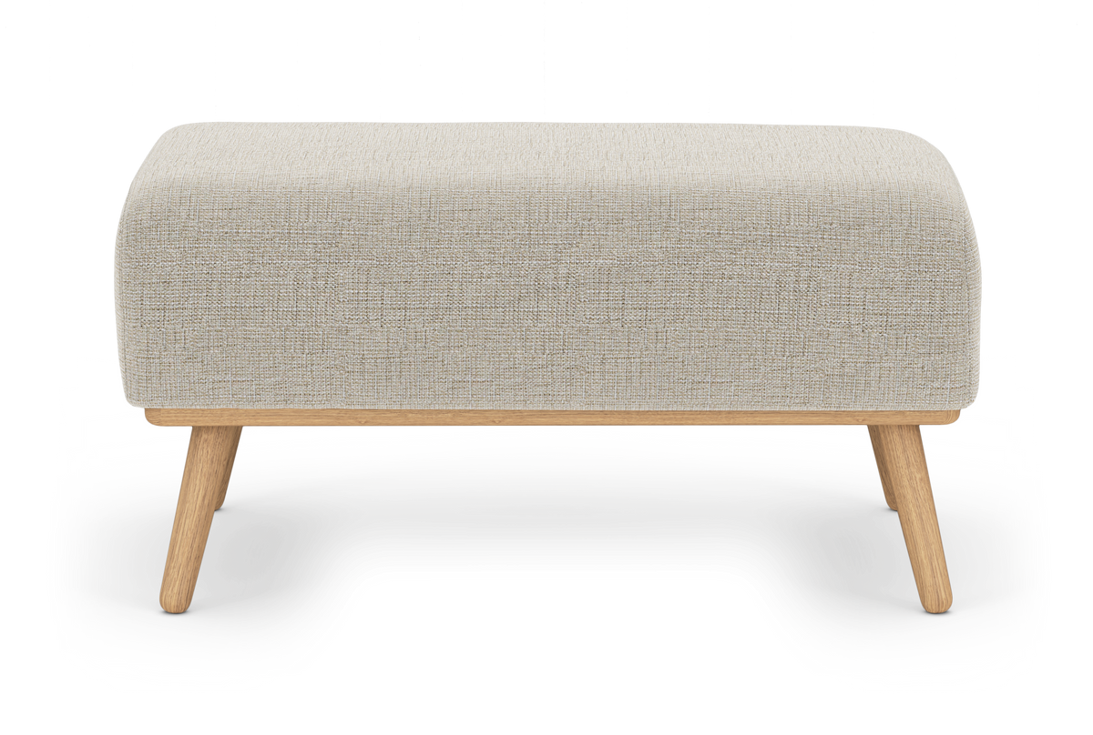 Beige stoppad ottoman med rundade hörn och ben i ljus ek, frilagd på vit bakgrund.