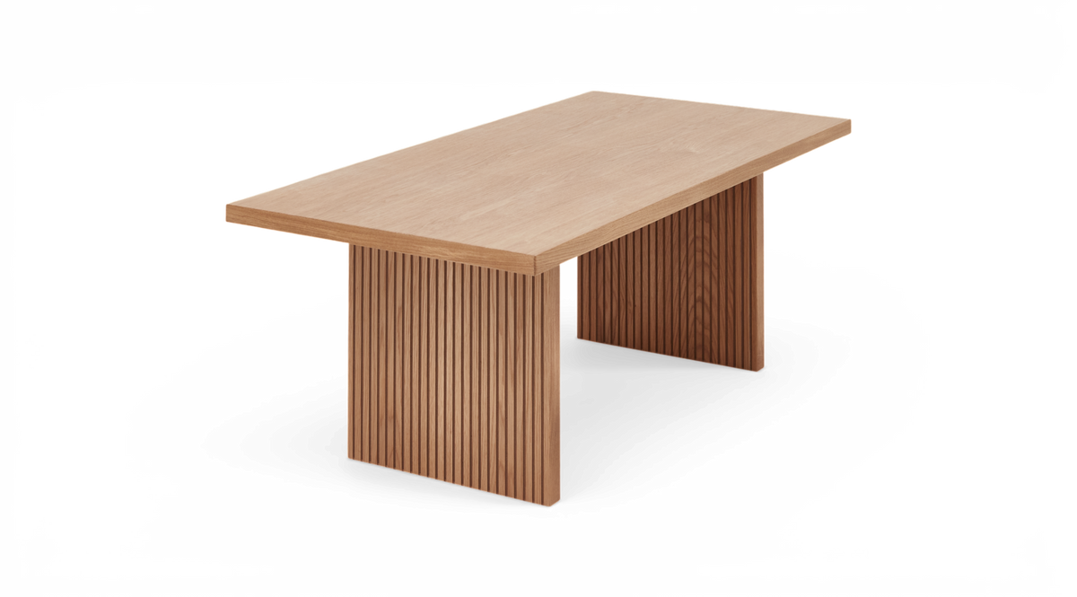 Rektangulärt matbord i ljus ek med ribbade panelben, visat i trekvartsvinkel.