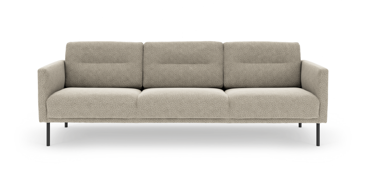 Beige tresits soffa med smala svarta metallben och mjuka, boxiga kuddar sedd rakt framifrån.