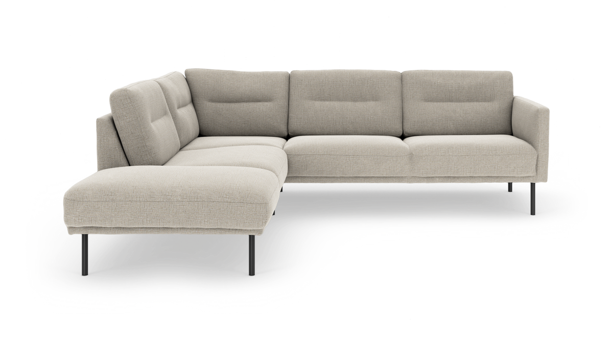 Beige L‑formad modulsoffa med slanka svarta metallben och mjukt tuftade ryggkuddar, visad i studio på vit bakgrund.