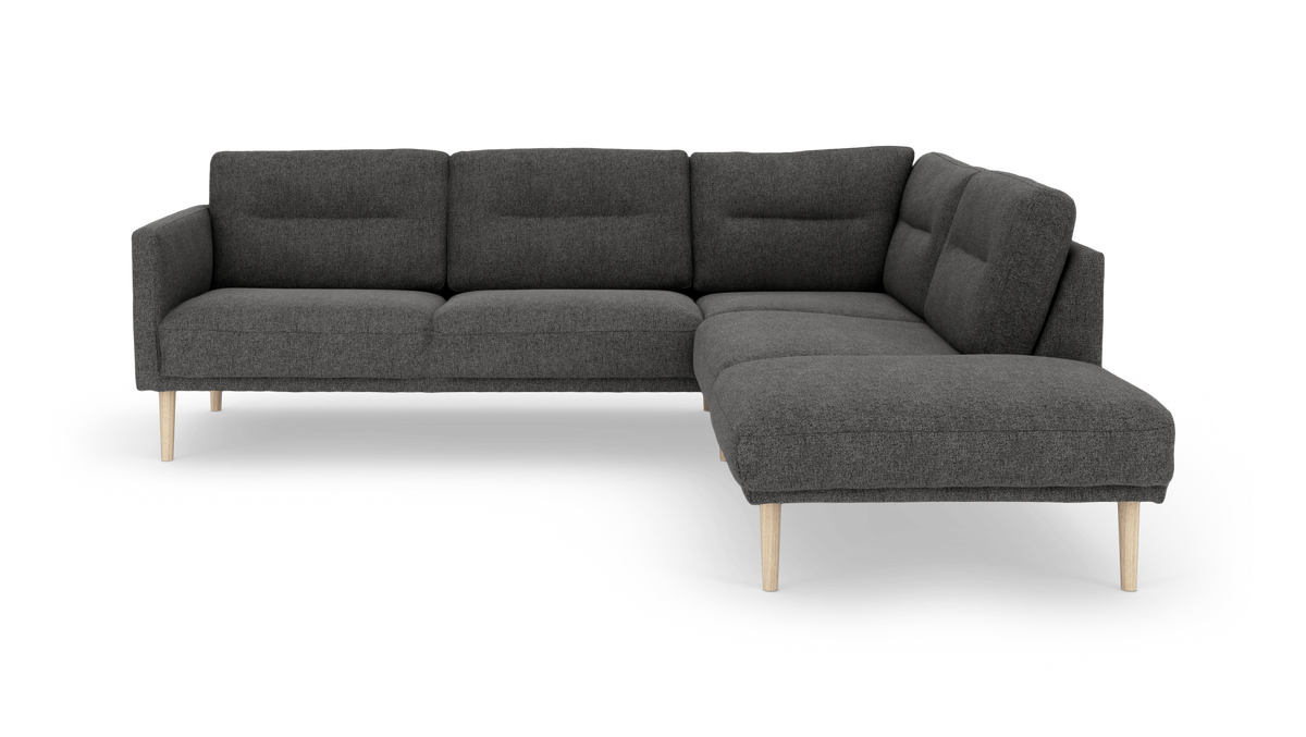 Mörkgrå L‑soffa med schäslong till höger och ljusa träben, minimalistisk design frilagd på vit bakgrund.