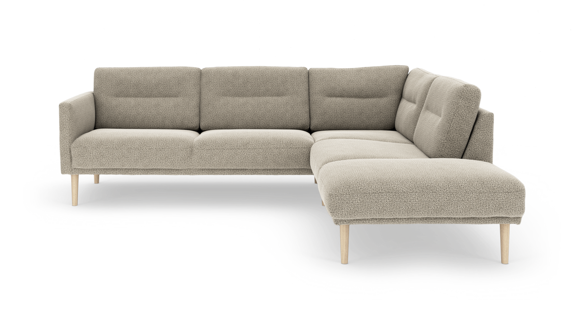 L-formad modulsoffa i beige bouclé med träben, frilagd på vit bakgrund.