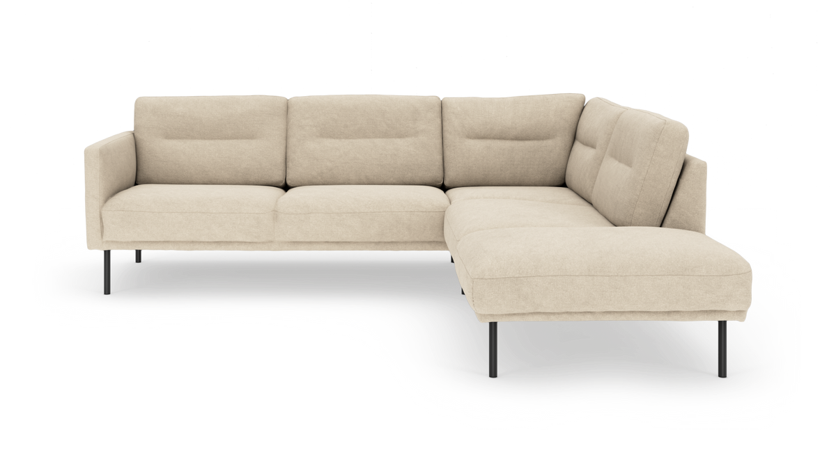 Beige L‑formad modulsoffa med schäslong till höger på höga svarta ben, frilagd mot vit bakgrund.