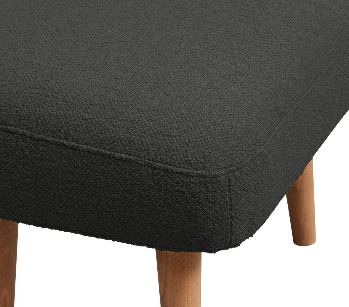 Närbild på mörkgrå stoppad pall/ottoman i bouclé med ben i ljust trä.