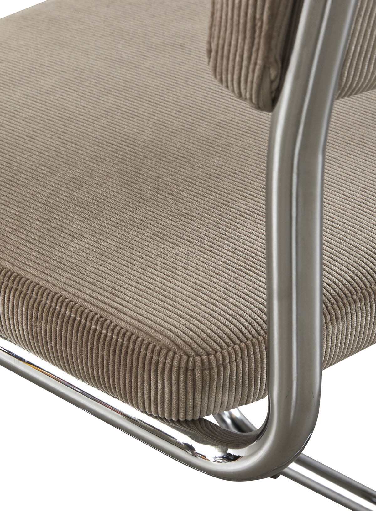 Närbild av beige ribbad sits i manchester på stol med kromat rörstativ.