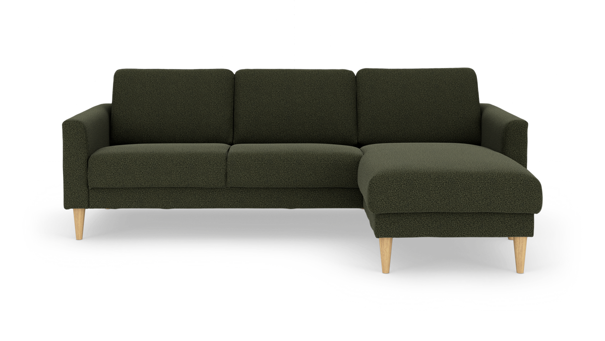 Mörkgrön modulsoffa med schäslong till höger, ljusa träben, frilagd på vit bakgrund.