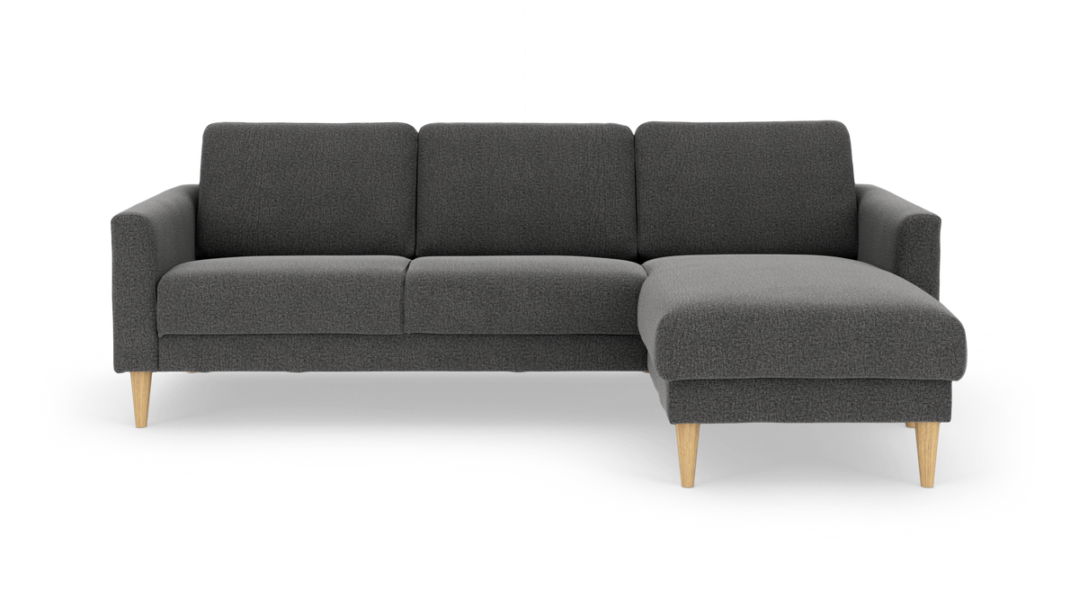 Mörkgrå L-formad 3-sits soffa med schäslong till höger och ljusa träben, frilagd på vit bakgrund.