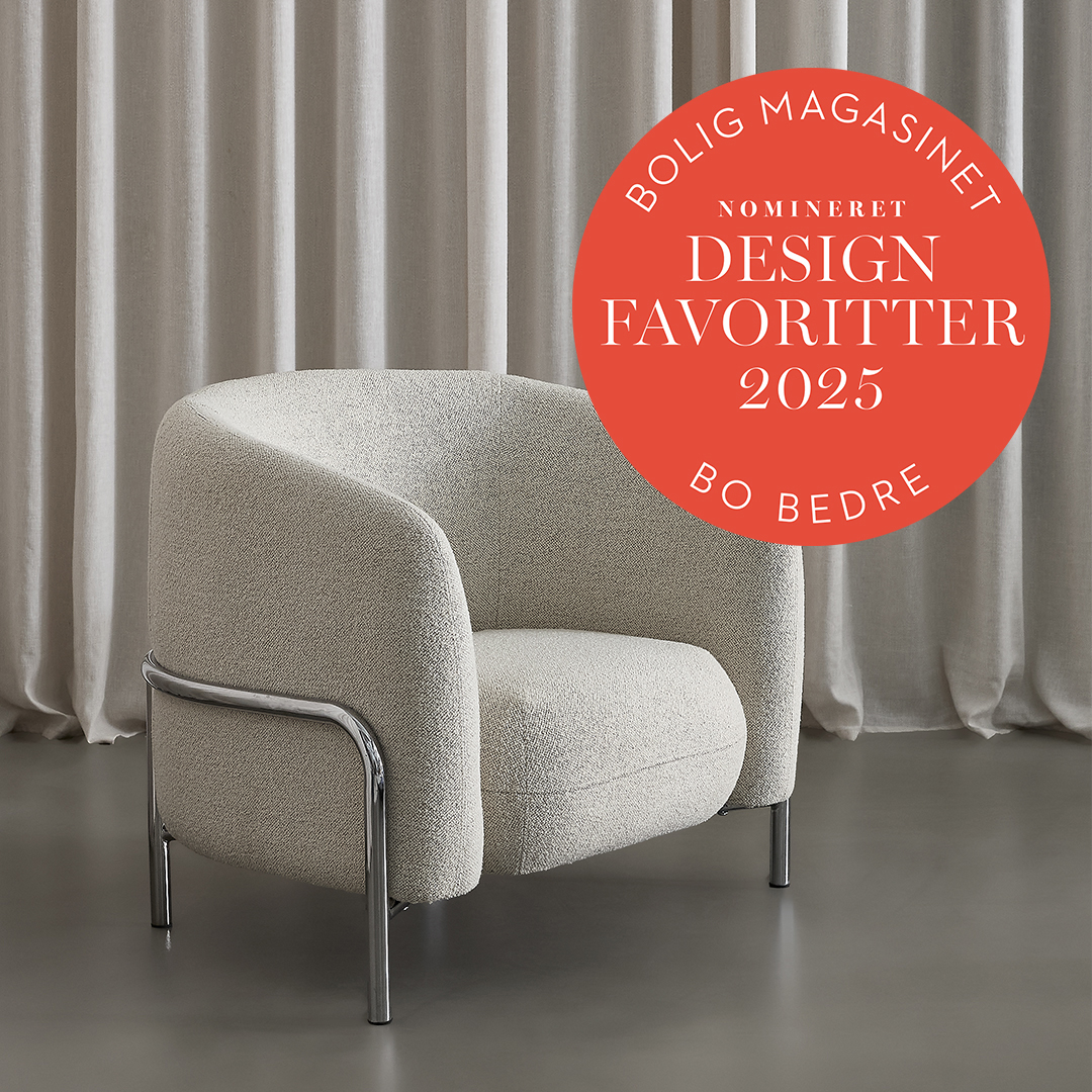 Ljusgrå fåtölj med kromben framför gråa gardiner, nominerad till Design Favoritter 2025 av Bolig Magasinet Bo Bedre.