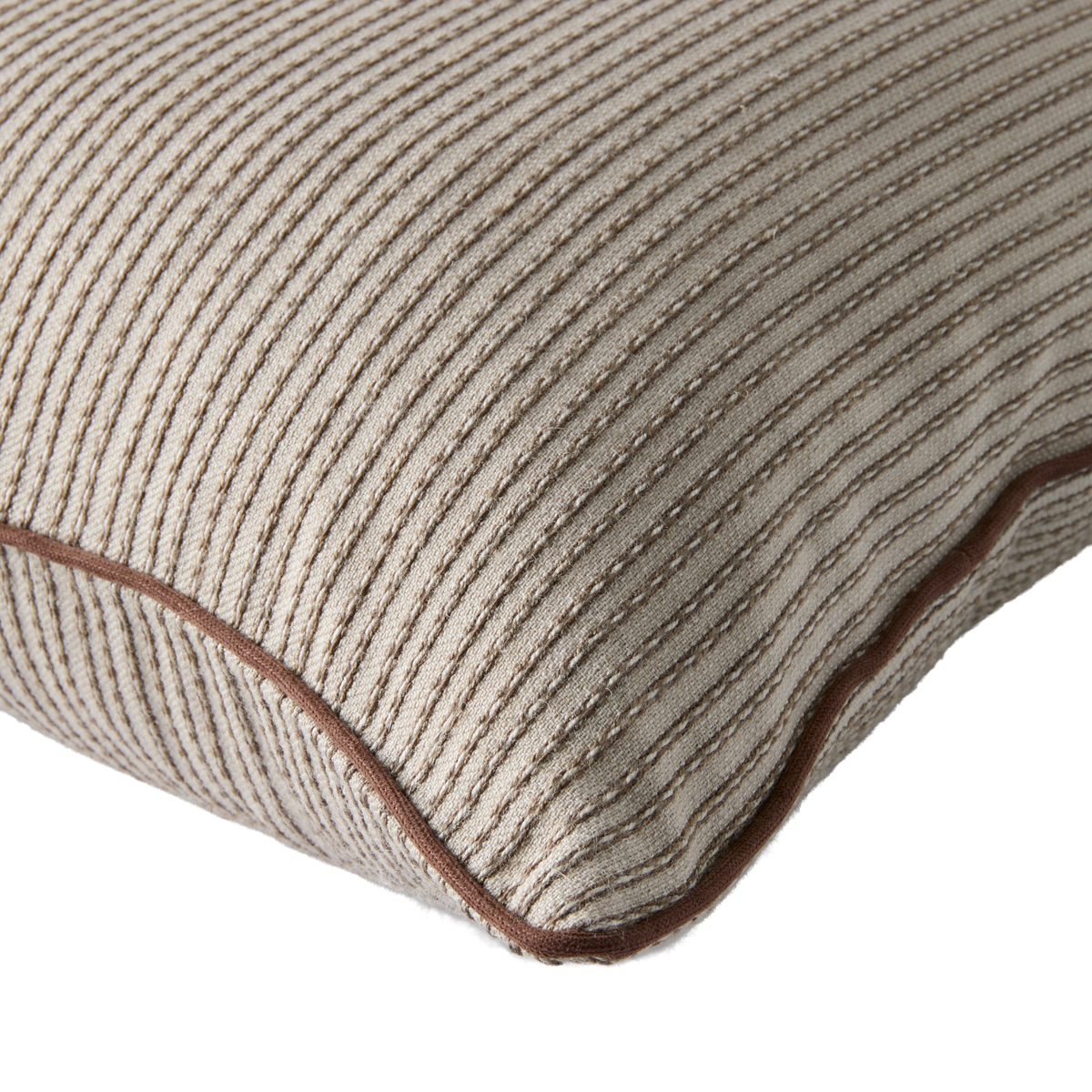 Närbild av beige kudde med ribbad textur och brun passpoal.