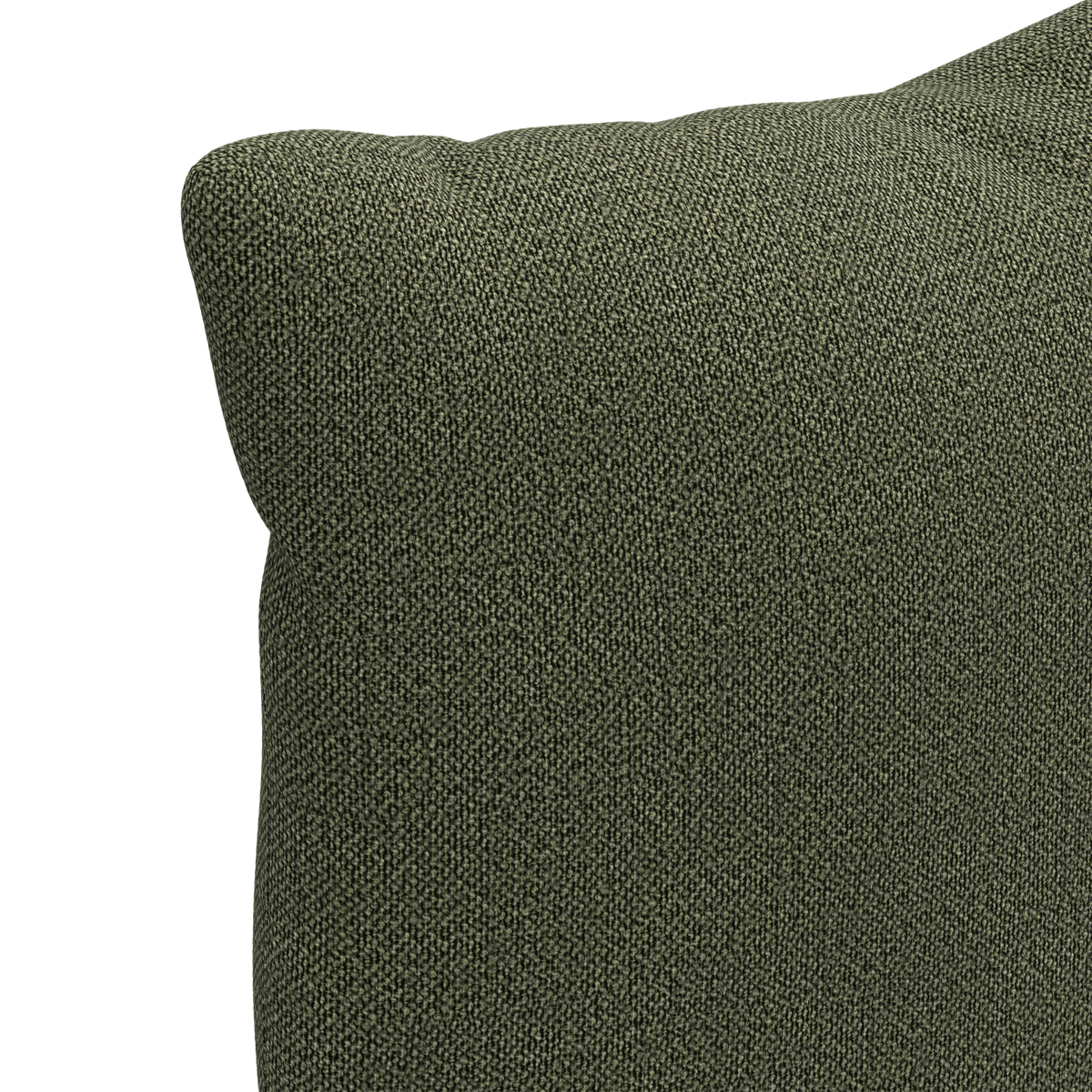 Närbild på hörnet av en grön, texturerad kudde mot vit bakgrund.