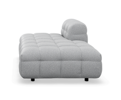 Grå tuftad modulsoffa/chaise med låg profil, frilagd på vit bakgrund.