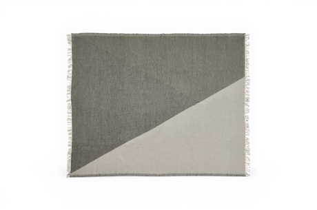 Grå-beige pläd med grafiskt triangulärt mönster och fransar längs kanterna.