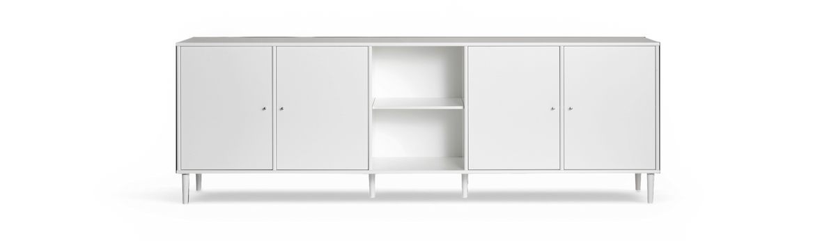 Vit sideboard med fyra dörrar och öppna hyllor i mitten, slanka ben, frilagd mot svart bakgrund.