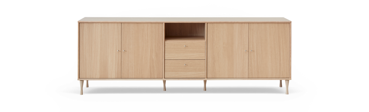 Sideboard i ljus ek med fyra dörrar, två lådor och öppen hylla, frilagd produktbild framifrån.