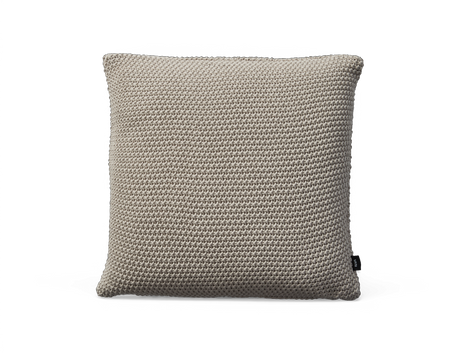 Beige stickad kudde med grov struktur, kvadratisk, frilagd.