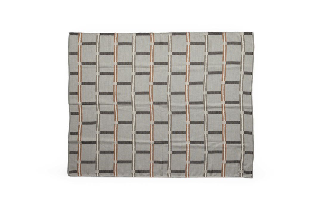 Rektangulärt tyg med rutmönster i grått, beige och rostbrunt, platt lagd mot mörk bakgrund.
