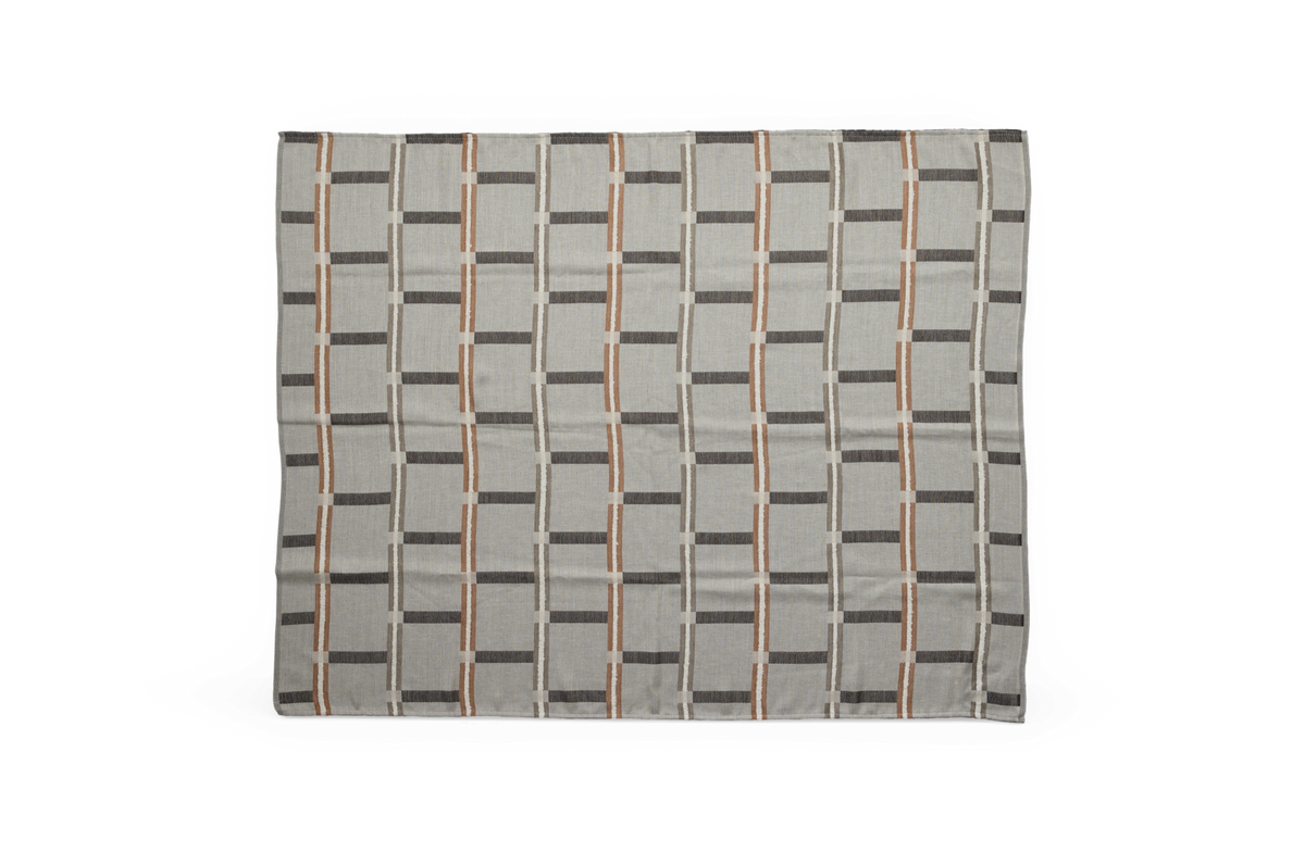 Rektangulärt tyg med rutmönster i grått, beige och rostbrunt, platt lagd mot mörk bakgrund.