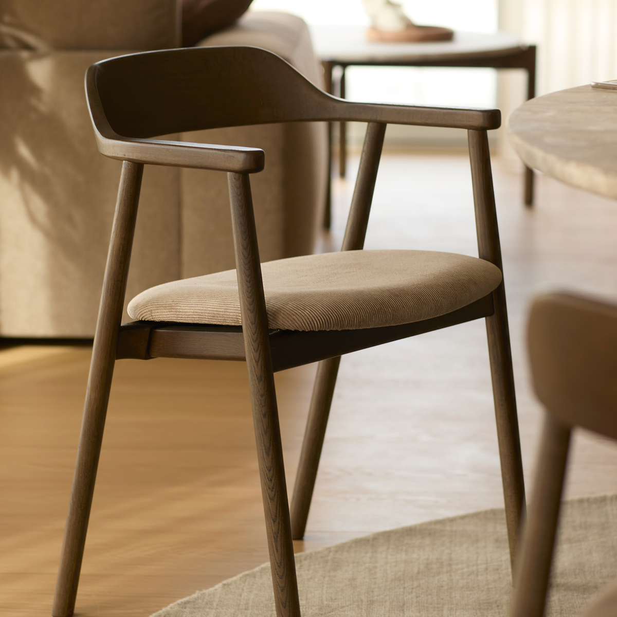 Modern brun trästol med beige sits i ett ljust vardagsrum.