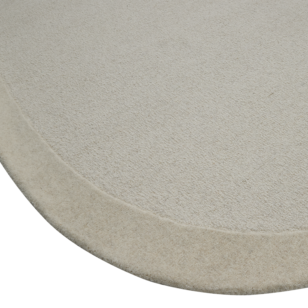 Närbild av rund ljusbeige matta med mjuk kant.