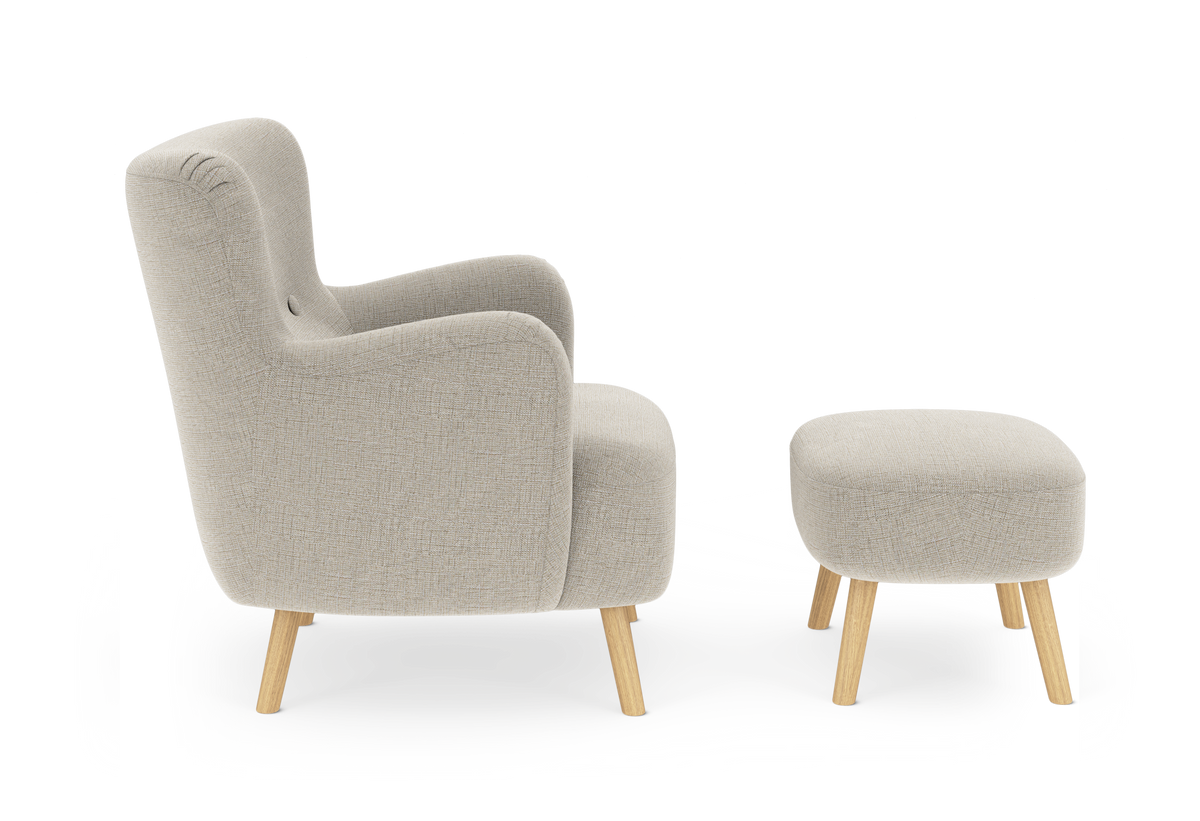 Beige fåtölj med matchande fotpall på träben, sedd från sidan.