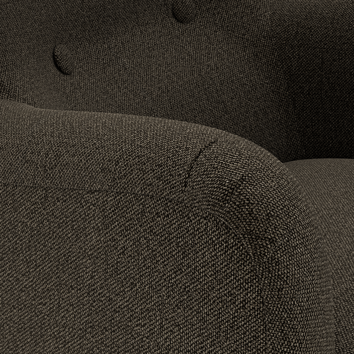 Närbild av en mörk, texturerad tygfåtölj med rundat armstöd och knapptuftad rygg.