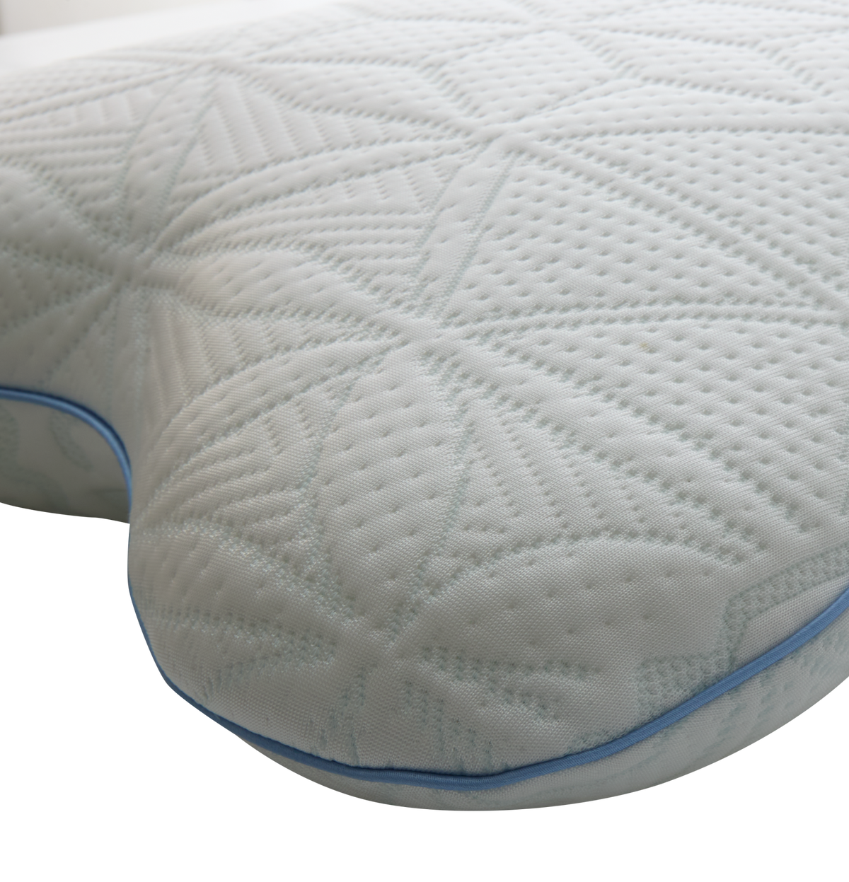 Närbild av en vit ergonomisk kudde med mönstrad, quiltad yta och blå passpoal.
