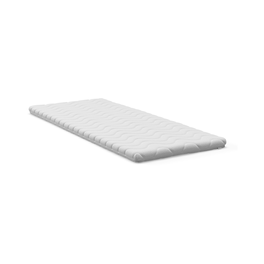 Vit bäddmadrass/topmadras med vågmönstrad quiltning på vit bakgrund.