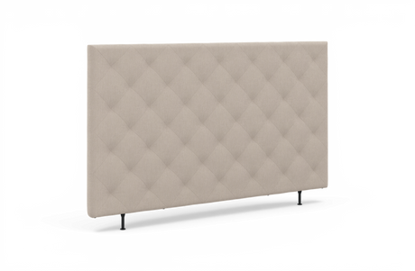 Beige, knappstoppad sänggavel med rutquiltning och smala svarta ben, frilagd i studio.