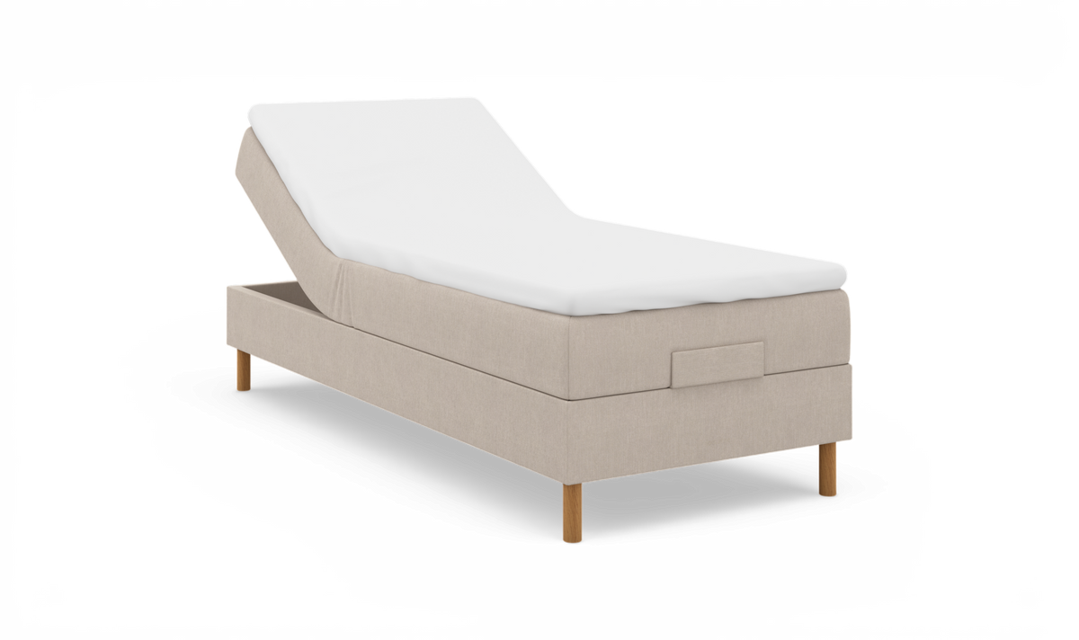 Justerbar säng i beige textil med vit madrass och träben, frilagd på vit bakgrund i sned vinkel.