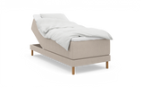 Beige ställbar säng med upphöjd huvuddel, vit bäddning och träben, frilagd på vit bakgrund._ps