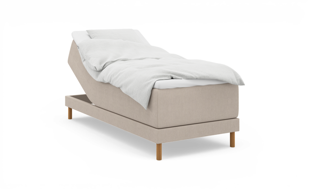 Beige ställbar säng med upphöjd huvuddel, vit bäddning och träben, frilagd på vit bakgrund.