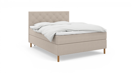 Beige kontinentalsäng med quiltad sänggavel, vit bäddning och träben, frilagd på neutral bakgrund.