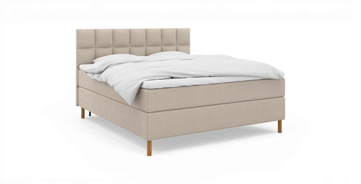 Beige stoppad säng med rutquiltad sänggavel, vit bäddning och träben, trekvarts vy mot vit bakgrund.