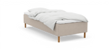 Enkel säng med beige stoppad sängram, vita sängkläder och träben, frilagd på vit bakgrund._ps