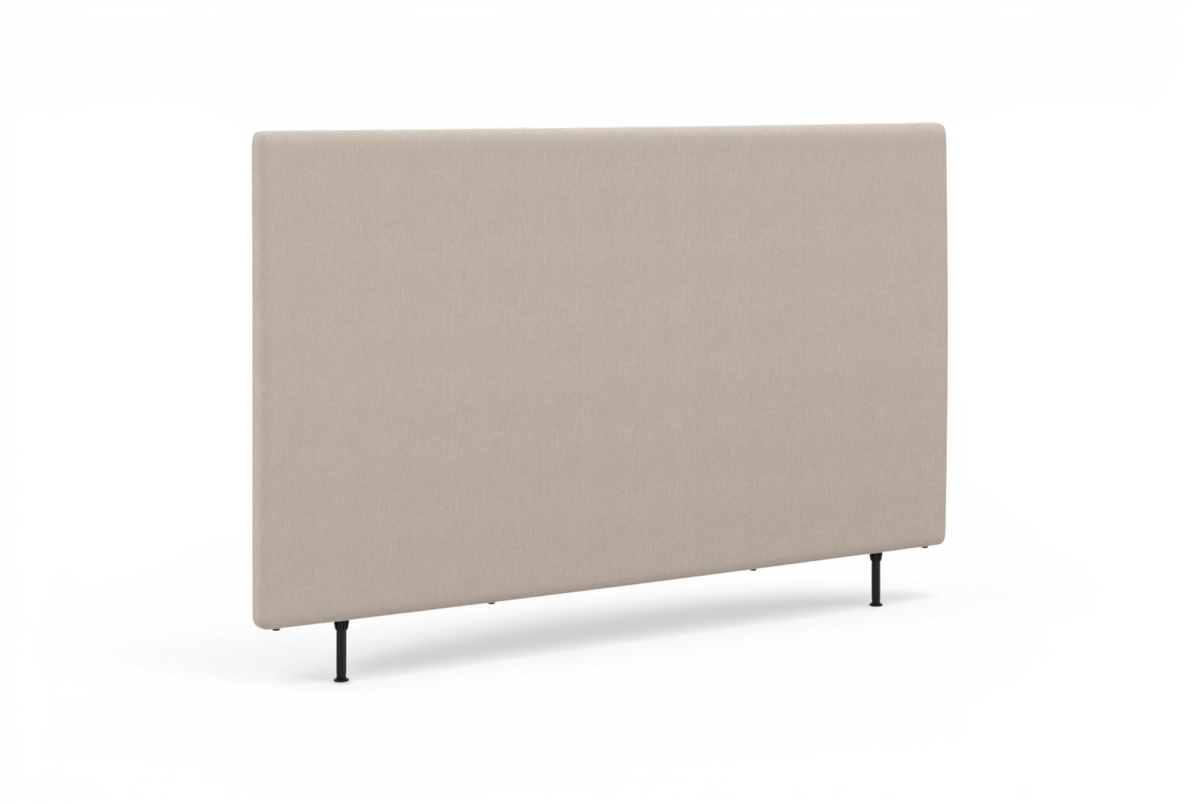 Beige sänggavel med textilklädsel och smala svarta ben, fotad i studio i lätt sned vinkel.
