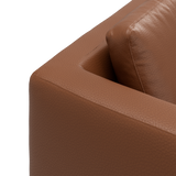 Närbild av brun lädersoffa – armstöd och ryggkudde.