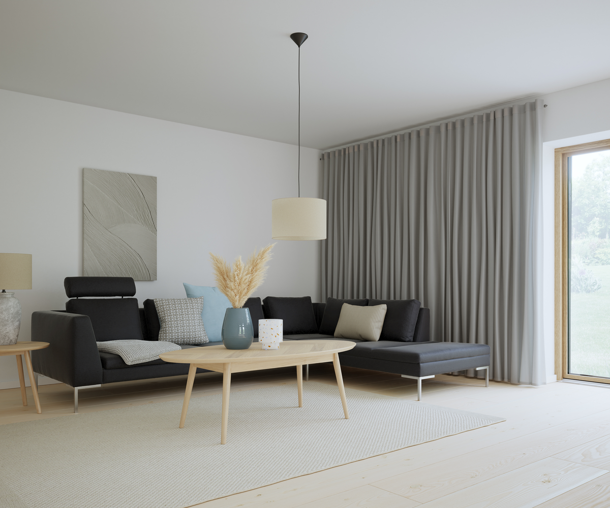 Ljus och luftig vardagsrumsscen med mörk modulsoffa, ljust träsbord, beige matta, grå gardiner och pendellampa; vas med pampasgräs och kuddar i blått och grått.